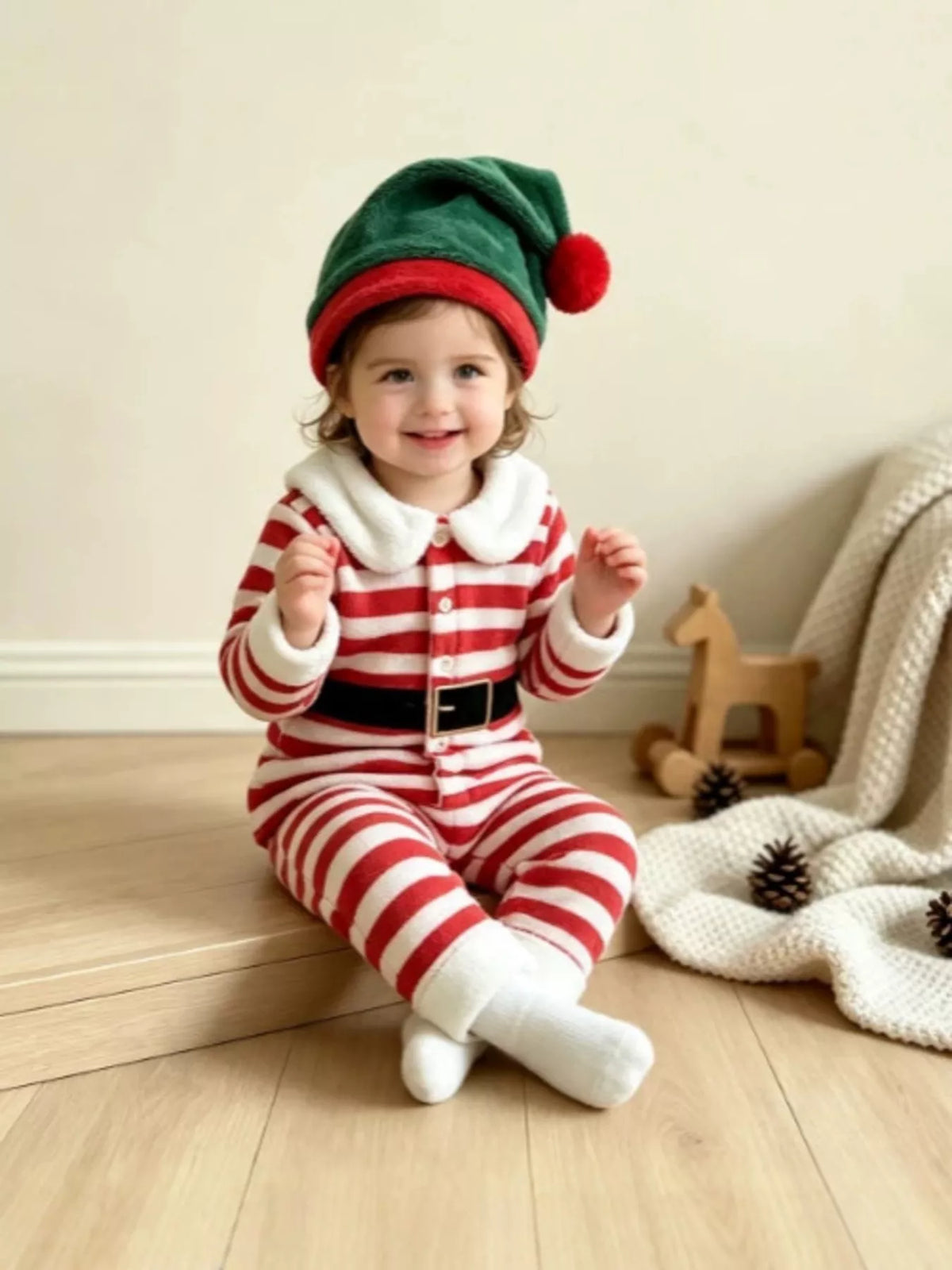 Red and white striped Christmas pajamas with printed black belt and green elf hat worn by a child