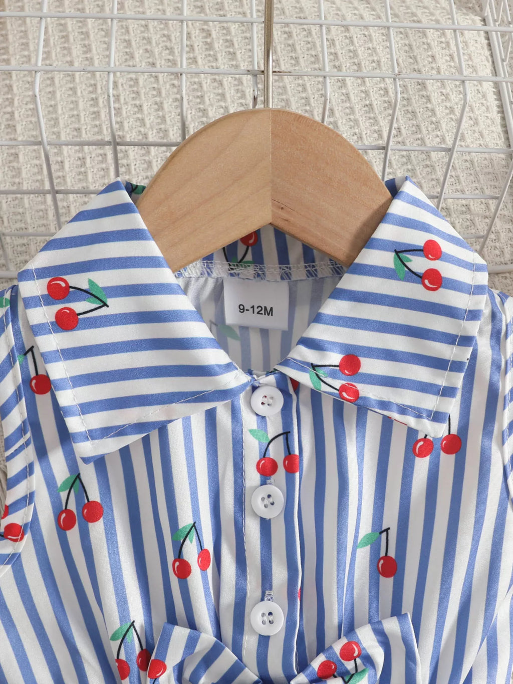 Close-up of the blue striped cherry-print romper's collar and buttons.