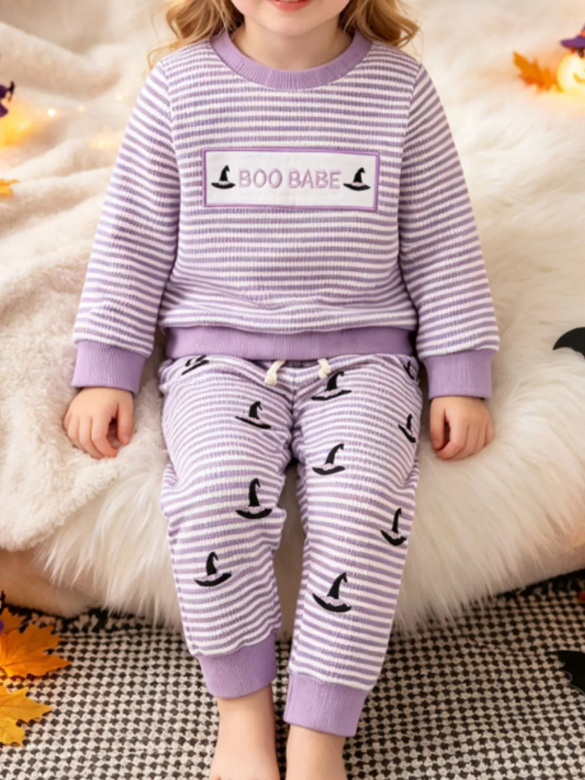 Purple striped BOO BABE pajama top and matching Halloween-print pants worn by a child