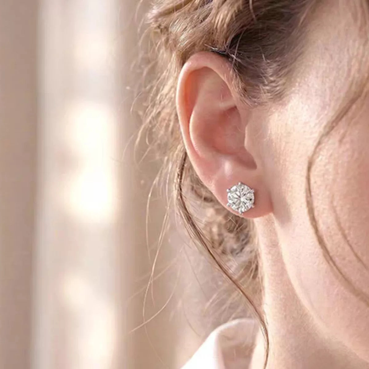 Silver-tone round clear stone stud earrings worn on a model