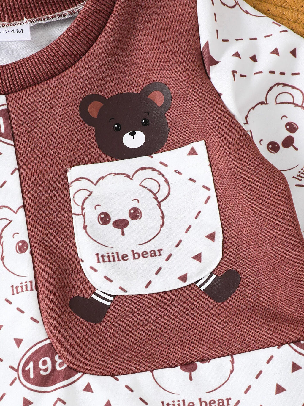 Bear chest-pocket graphic and maroon trim on the cream sweatshirt