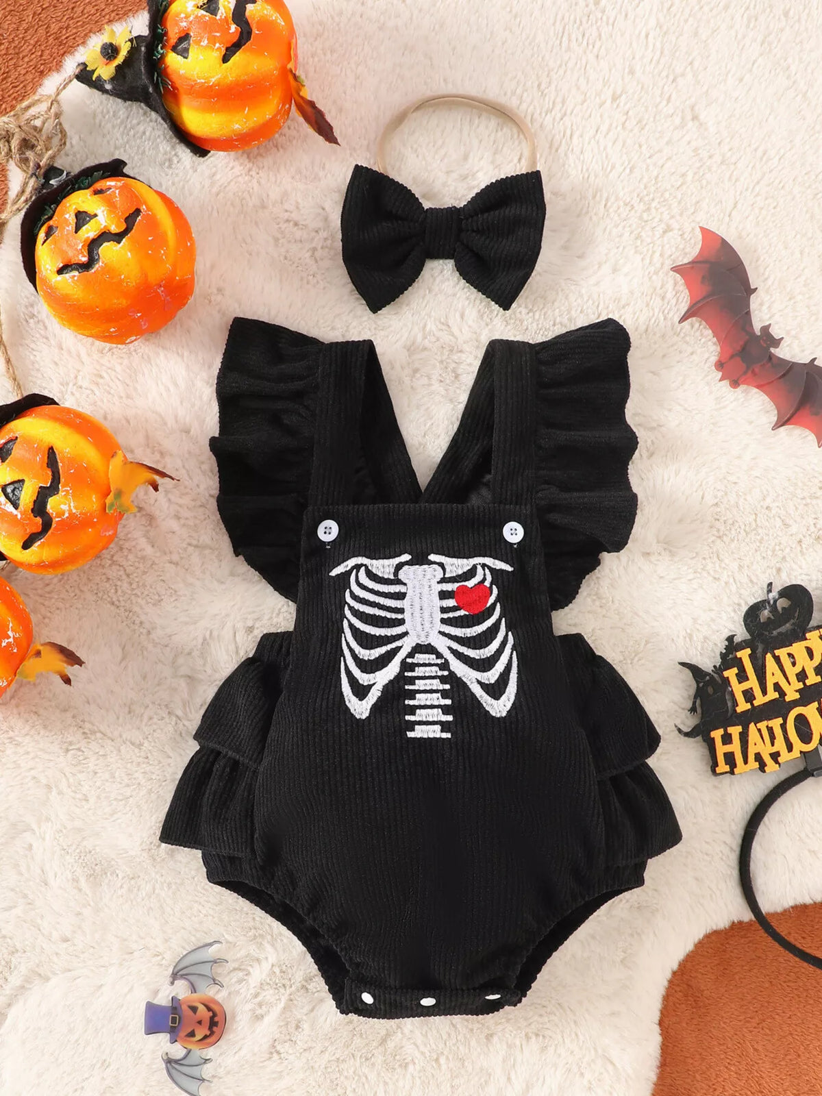 Black skeleton-print ruffle baby bodysuit and matching bow headband displayed flat