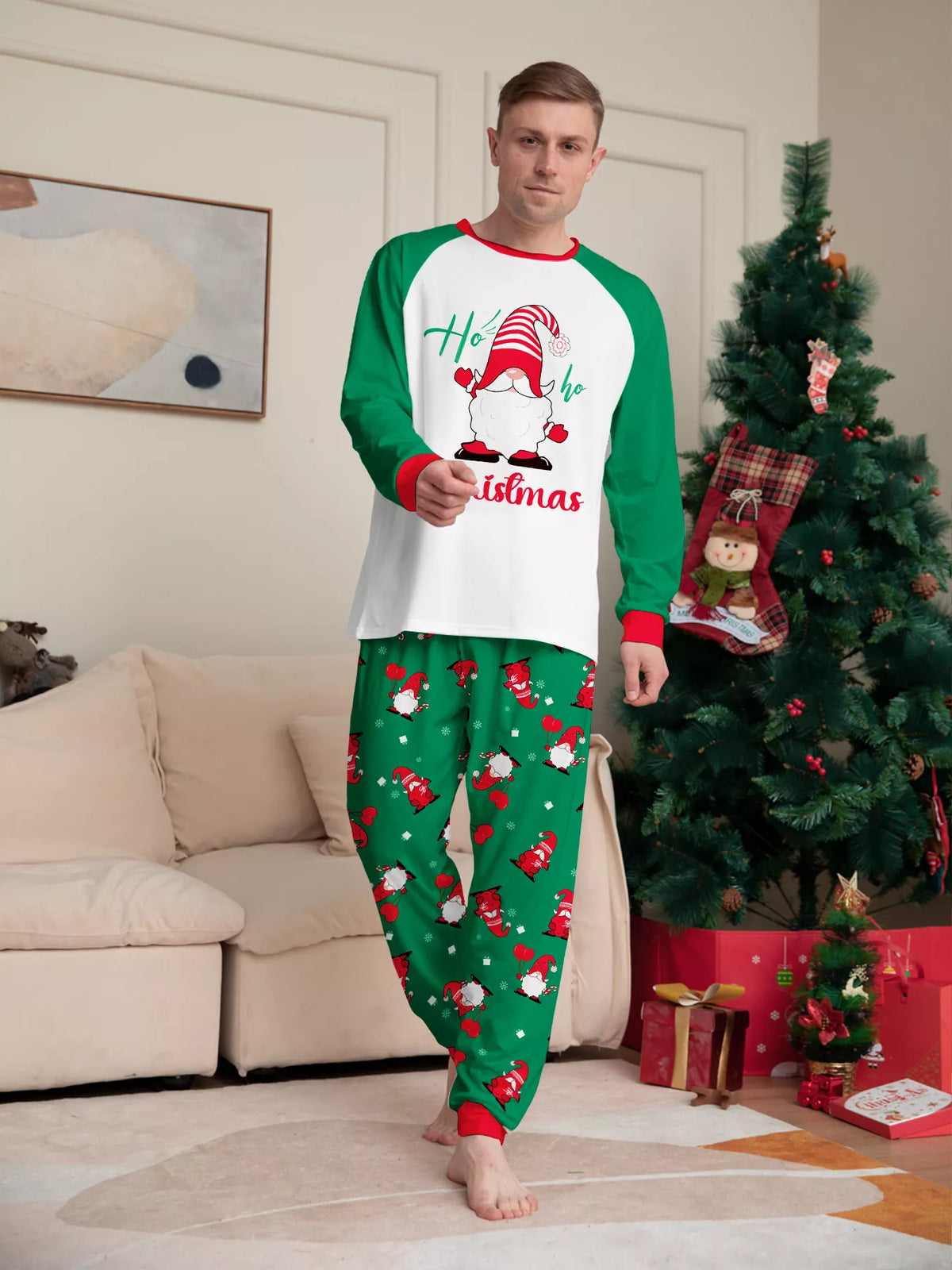Man modeling a white Christmas graphic top with green sleeves and green printed pajama pants.