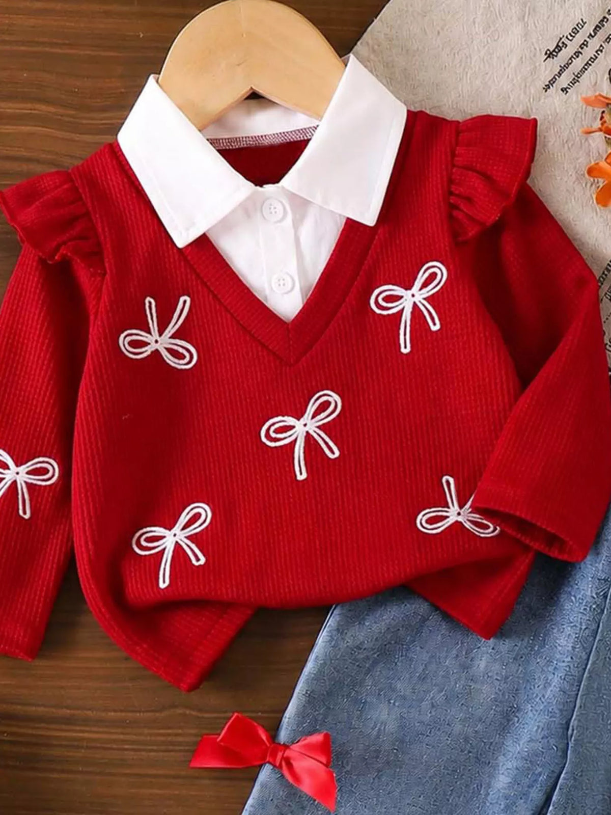 White pointed collar and small bow embellishments on the red sweater