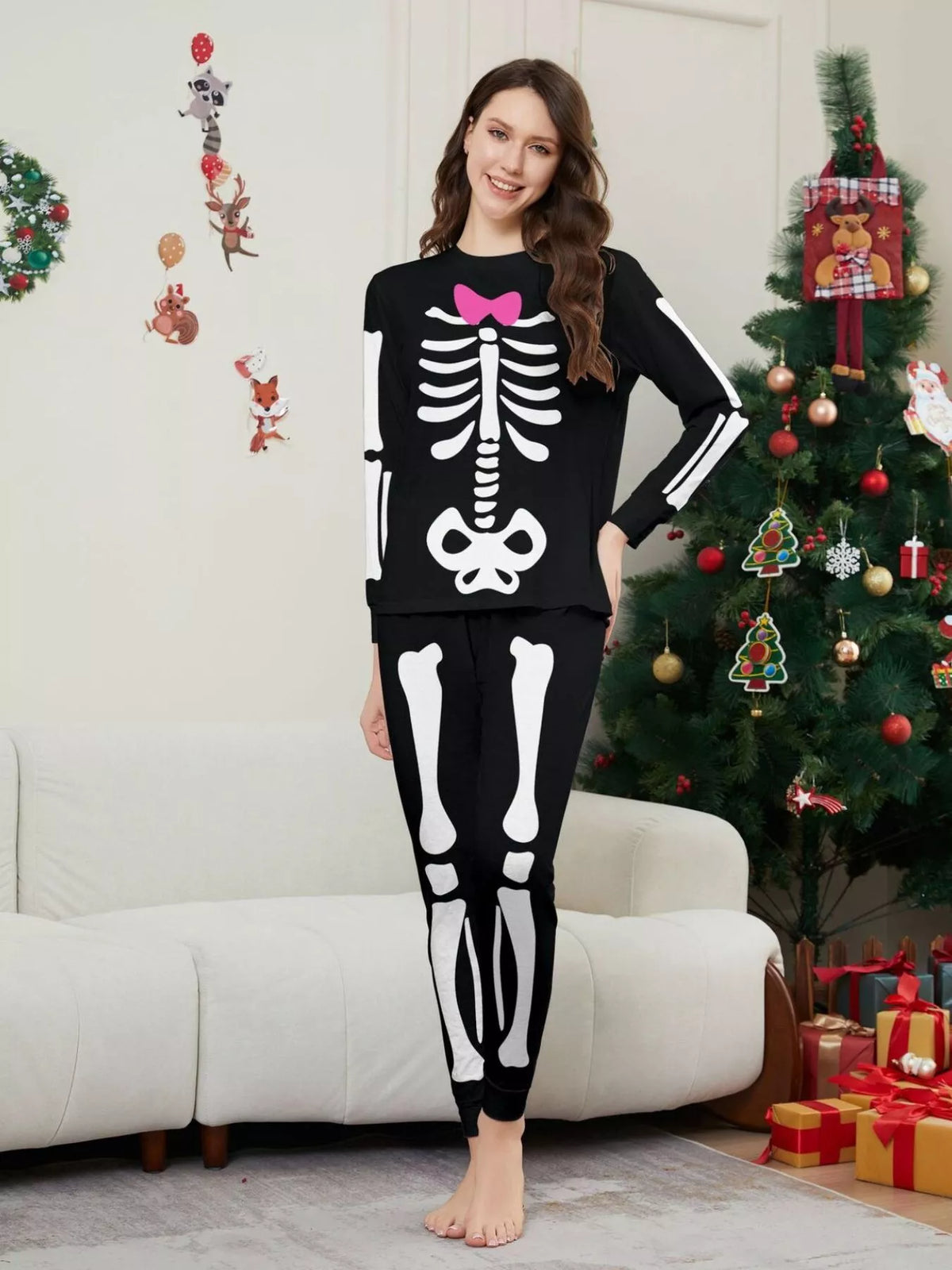 Woman modeling black pajamas with white skeleton graphics and a pink bow.
