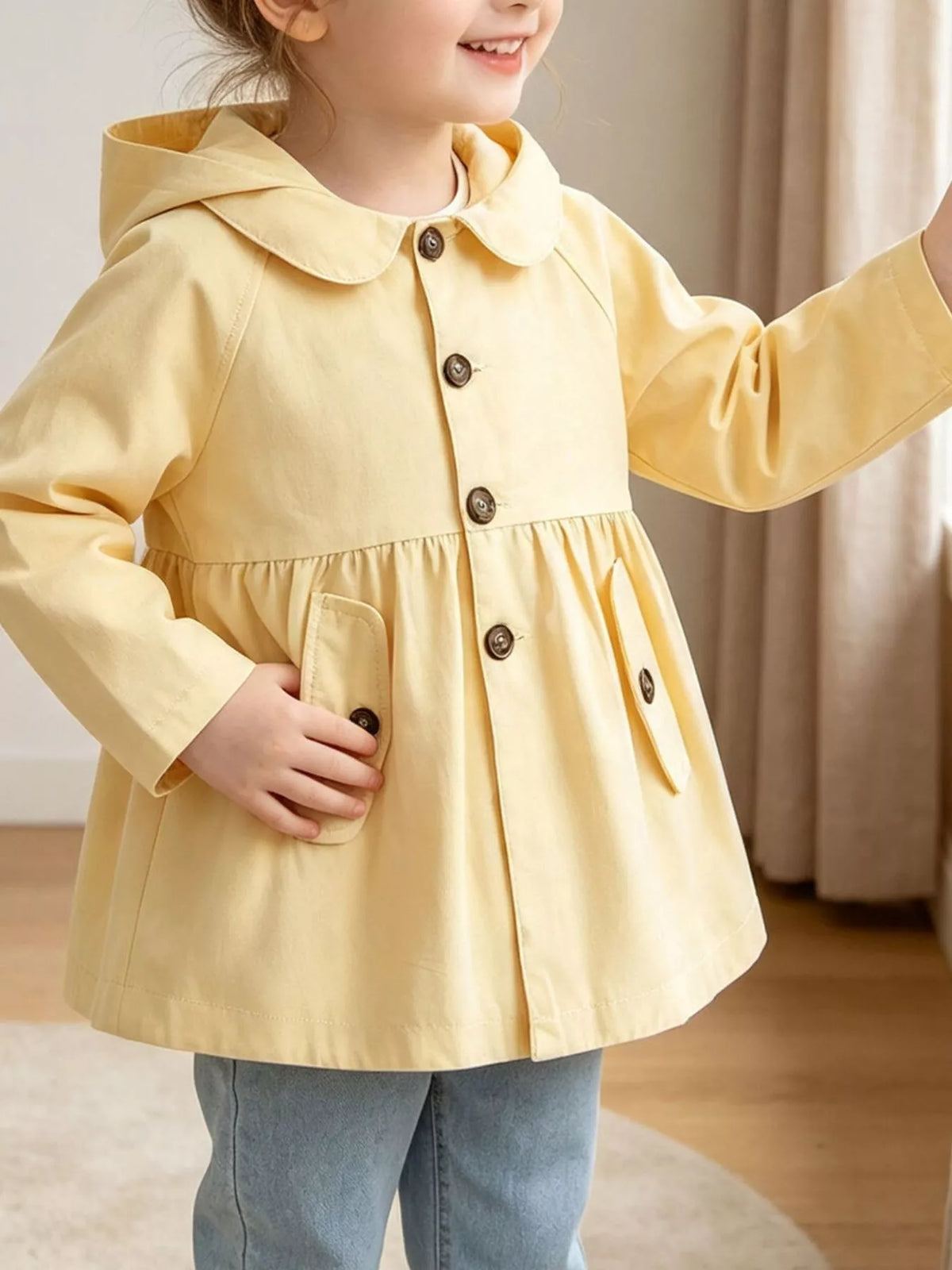 Yellow hooded peplum coat with button front worn by a child