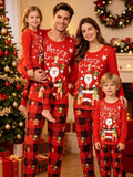 Family wearing matching red Merry Christmas tops and red plaid pajama pants beside a tree.