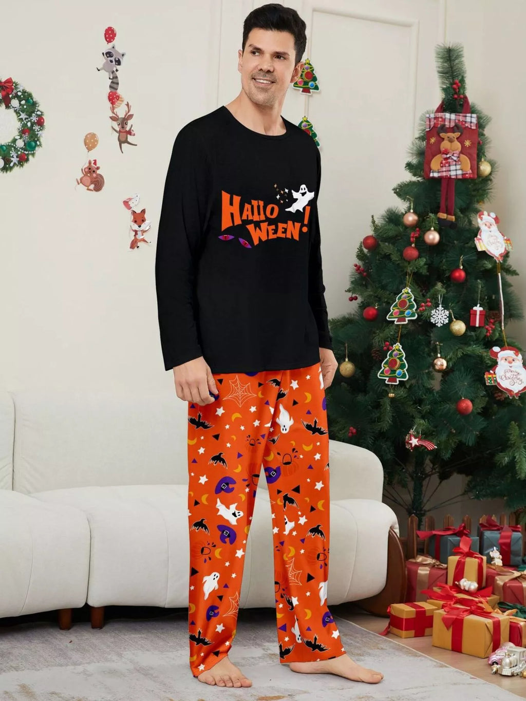Man modeling a black Halloween graphic pajama top with orange printed pants.