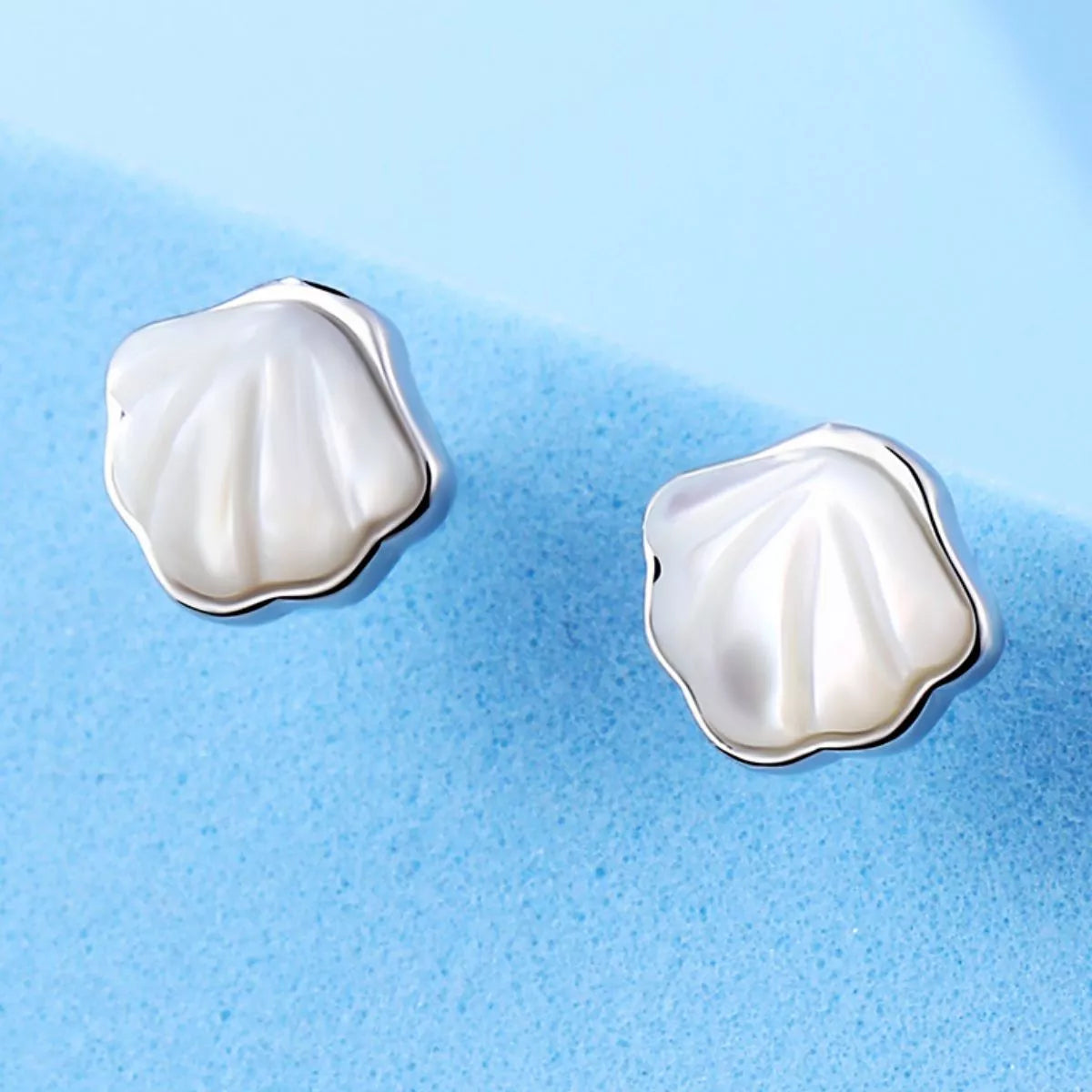 Silver-tone shell-shaped stud earrings with white centers — detail view