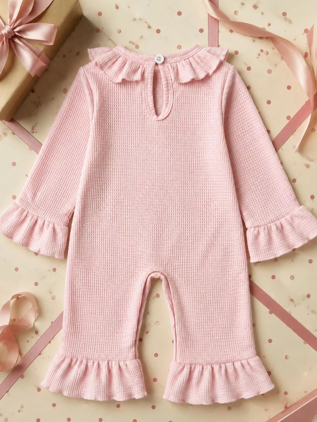Back view of the pink baby romper with ruffle collar and neckline opening.