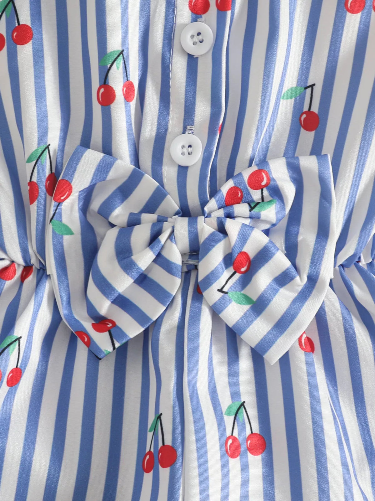 Close-up of the blue cherry-print romper's waist tie and button front.