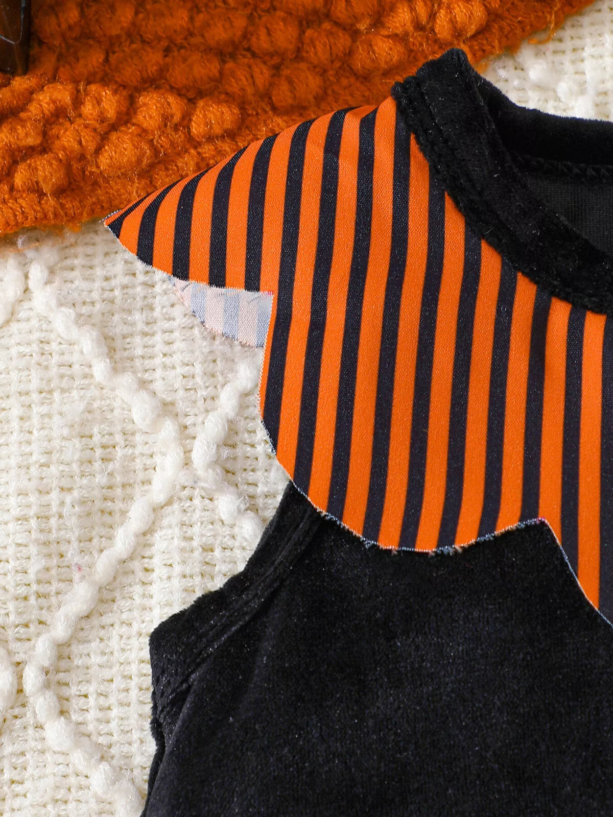 Orange and black striped shoulder detail on the black baby bodysuit