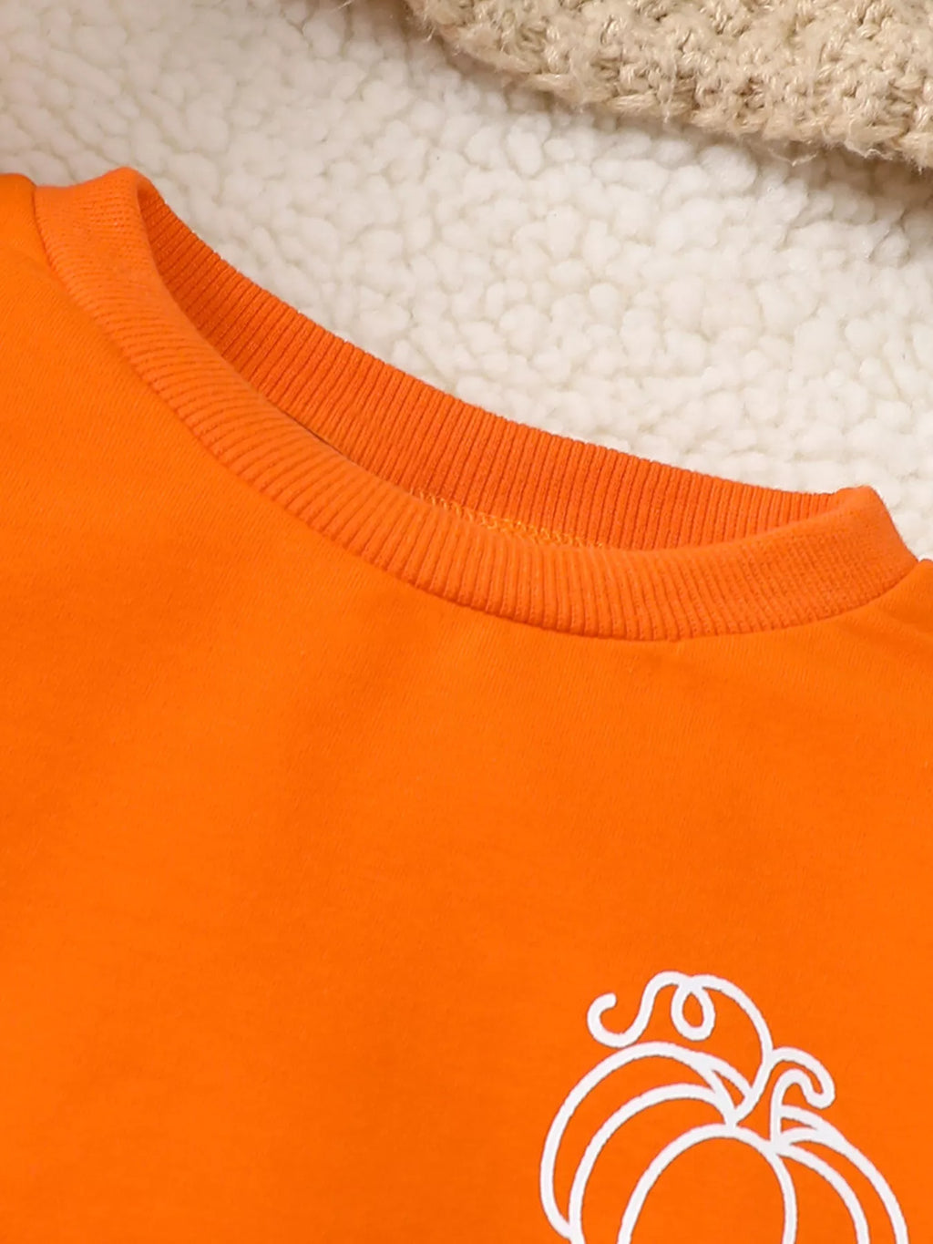 Orange crew neckline and white pumpkin graphic on the sweatshirt