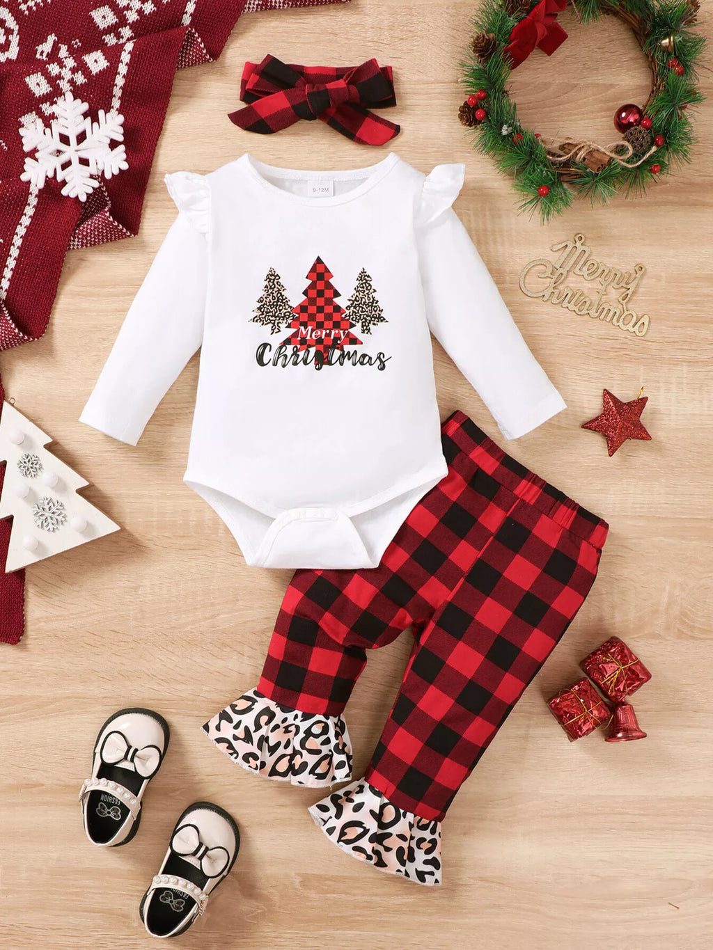 Flat lay of a white Christmas tree graphic bodysuit, plaid pants with leopard cuffs and bow headband.