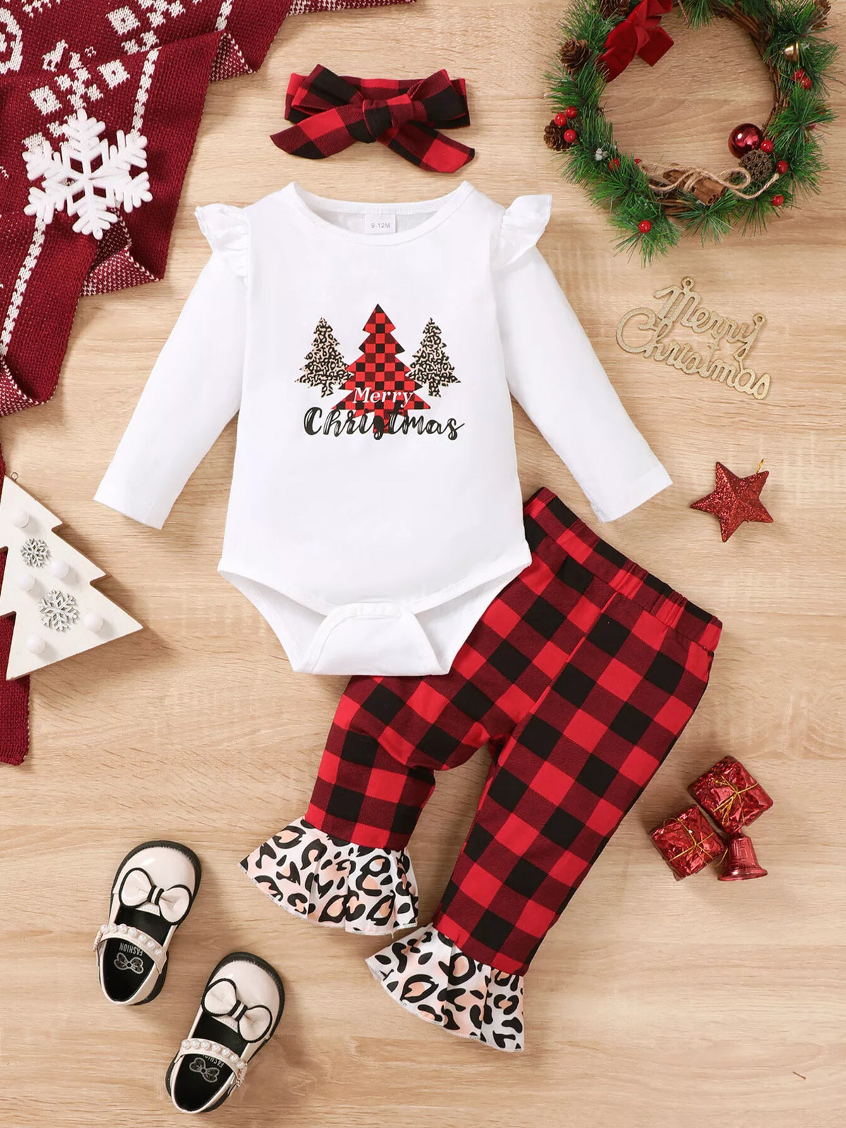 Flat lay of a white Christmas tree graphic bodysuit, plaid pants with leopard cuffs and bow headband.