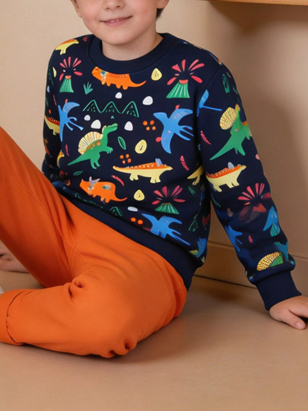 Seated child wearing the navy multicolor dinosaur-print sweatshirt.