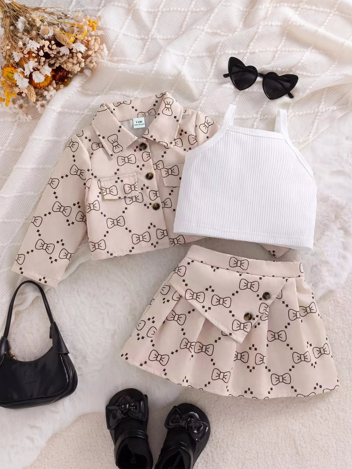 Children’s bow-print jacket and pleated skirt with a white ribbed tank displayed flat