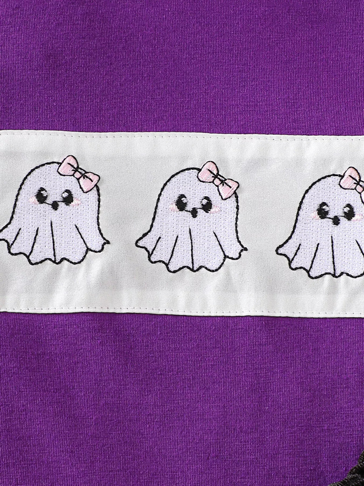 Close-up of three white ghosts with pink bows on the purple top.