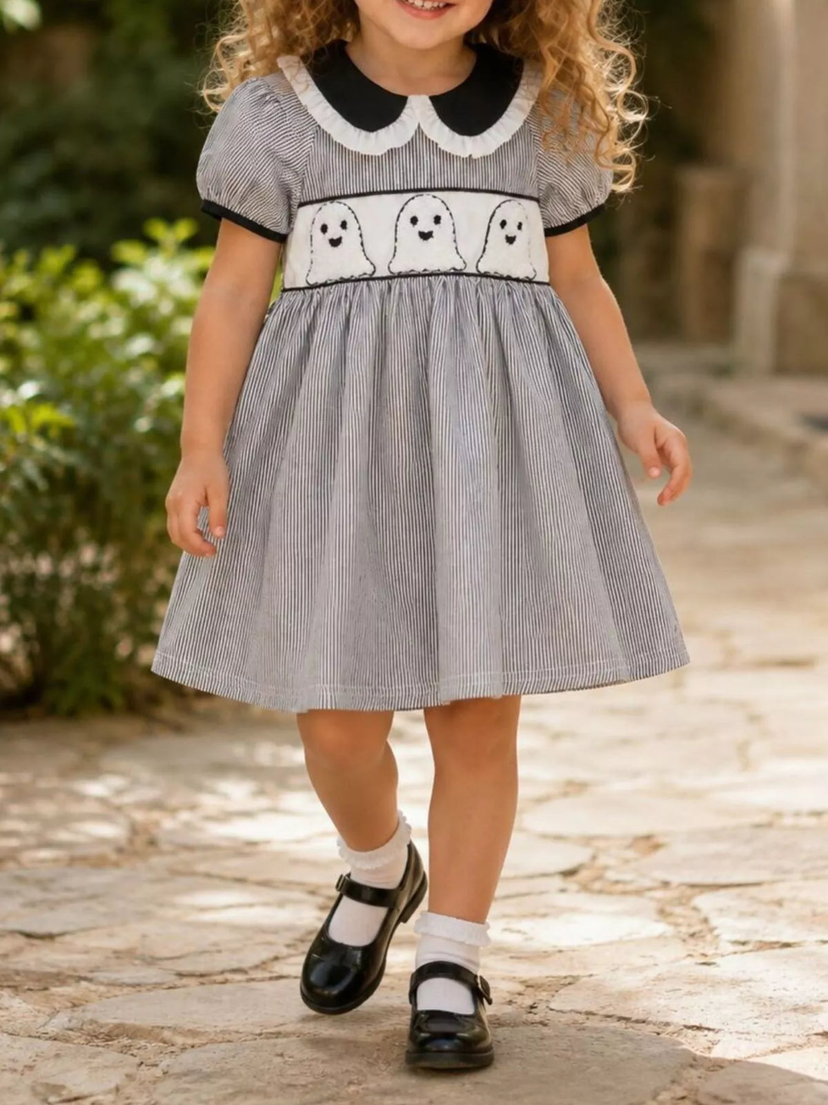 Front view of a child modeling the gray ghost-print Halloween dress.