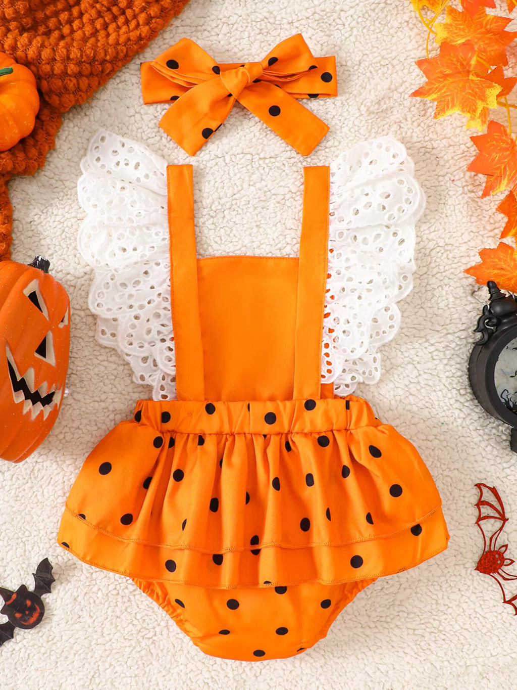 Back flat lay of the orange pumpkin romper with white eyelet trim and matching bow.