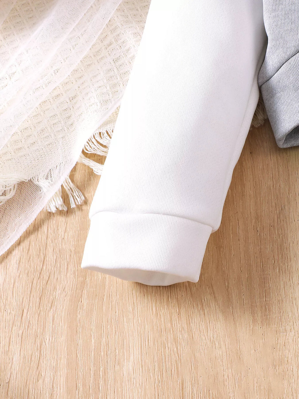 White cuff and sleeve detail on the gray hoodie