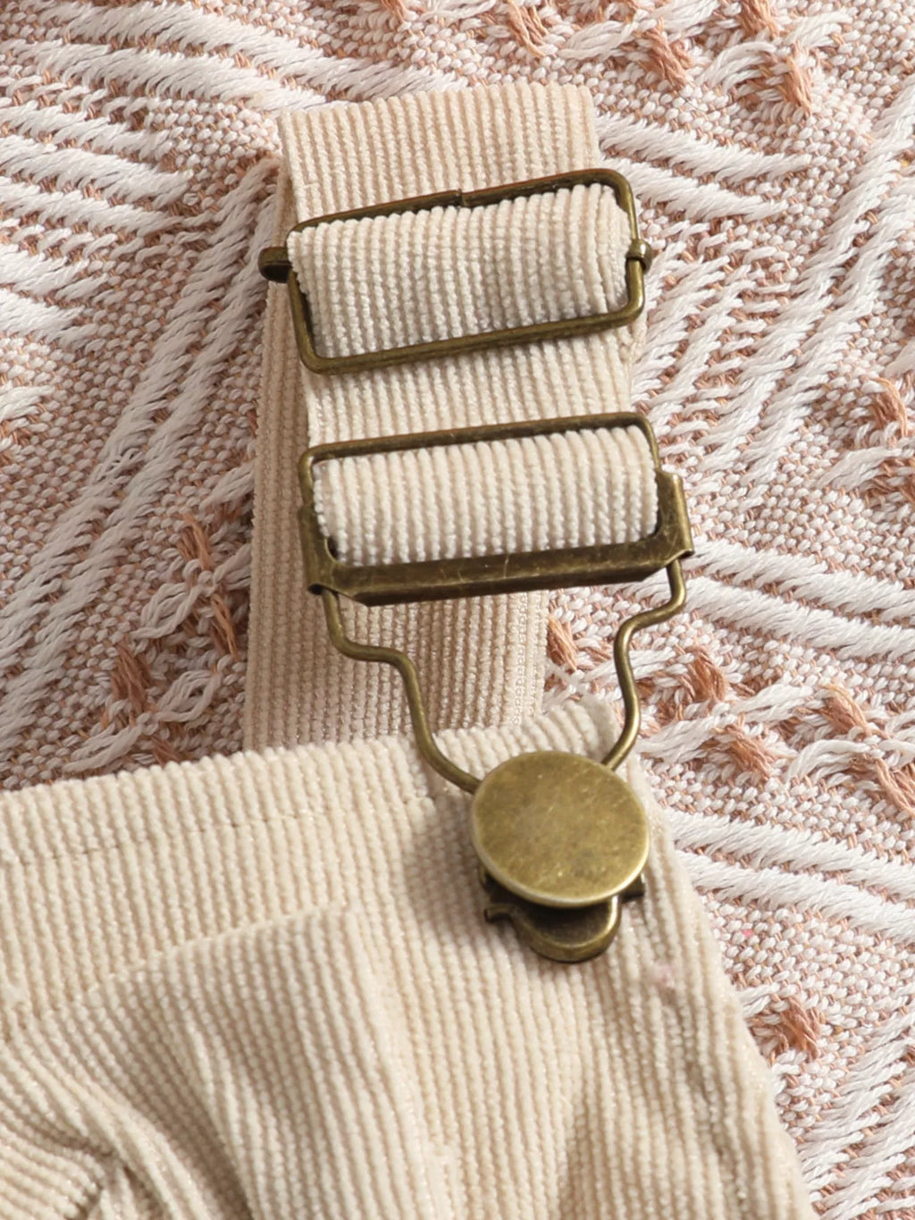 Adjustable strap clasp on the beige ribbed overalls