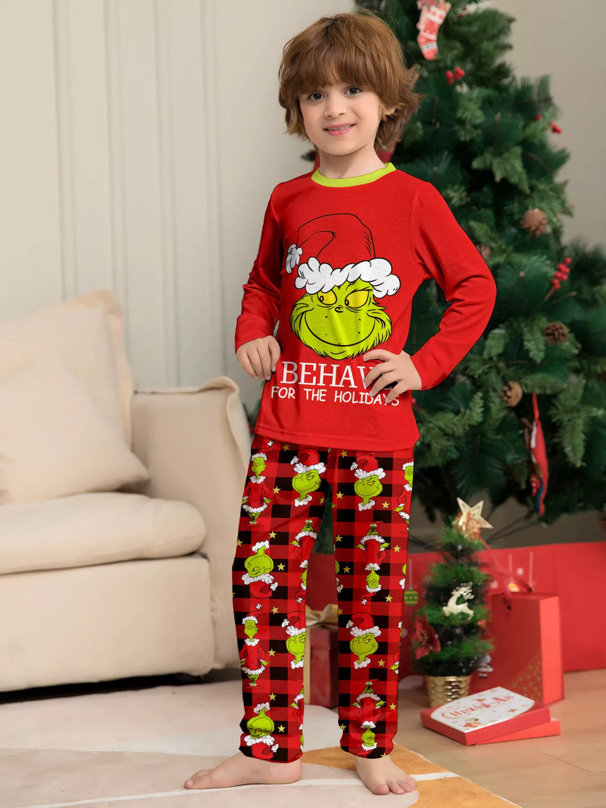 Red matching family Grinch graphic pajama top and Christmas-print pants worn by a child