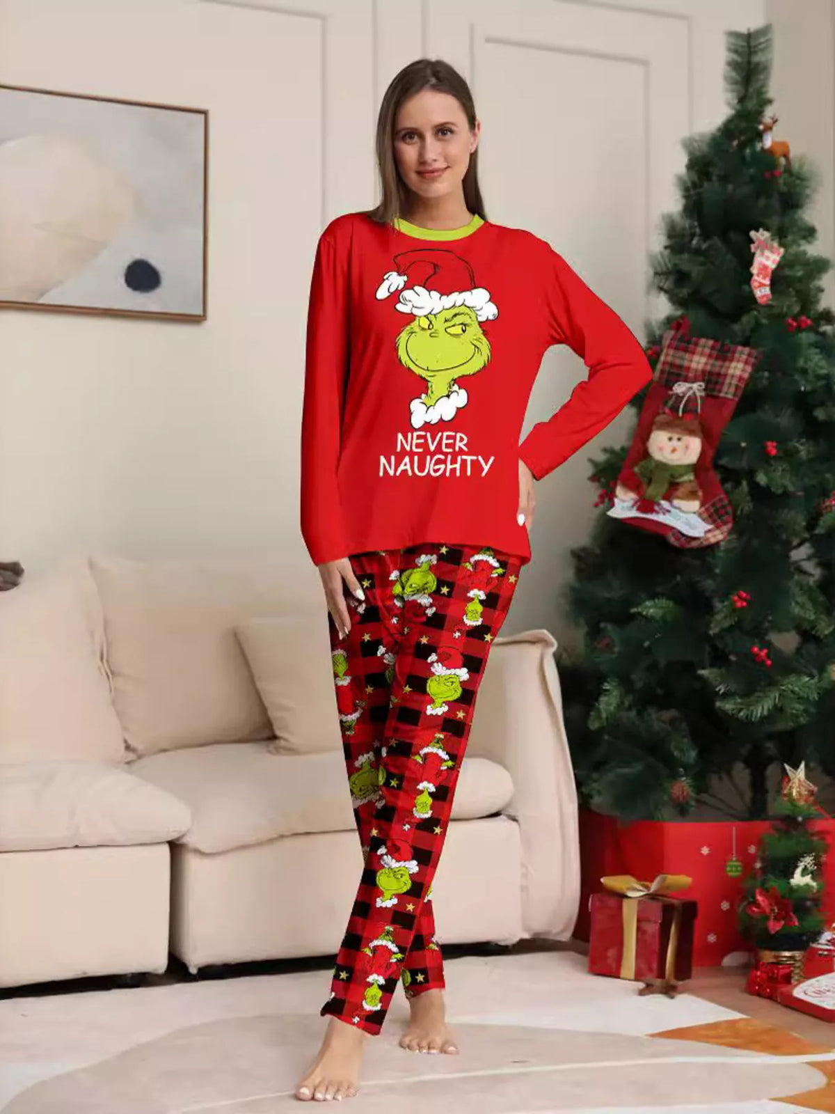 Red matching family Grinch graphic pajama top and Christmas-print pants worn by an adult
