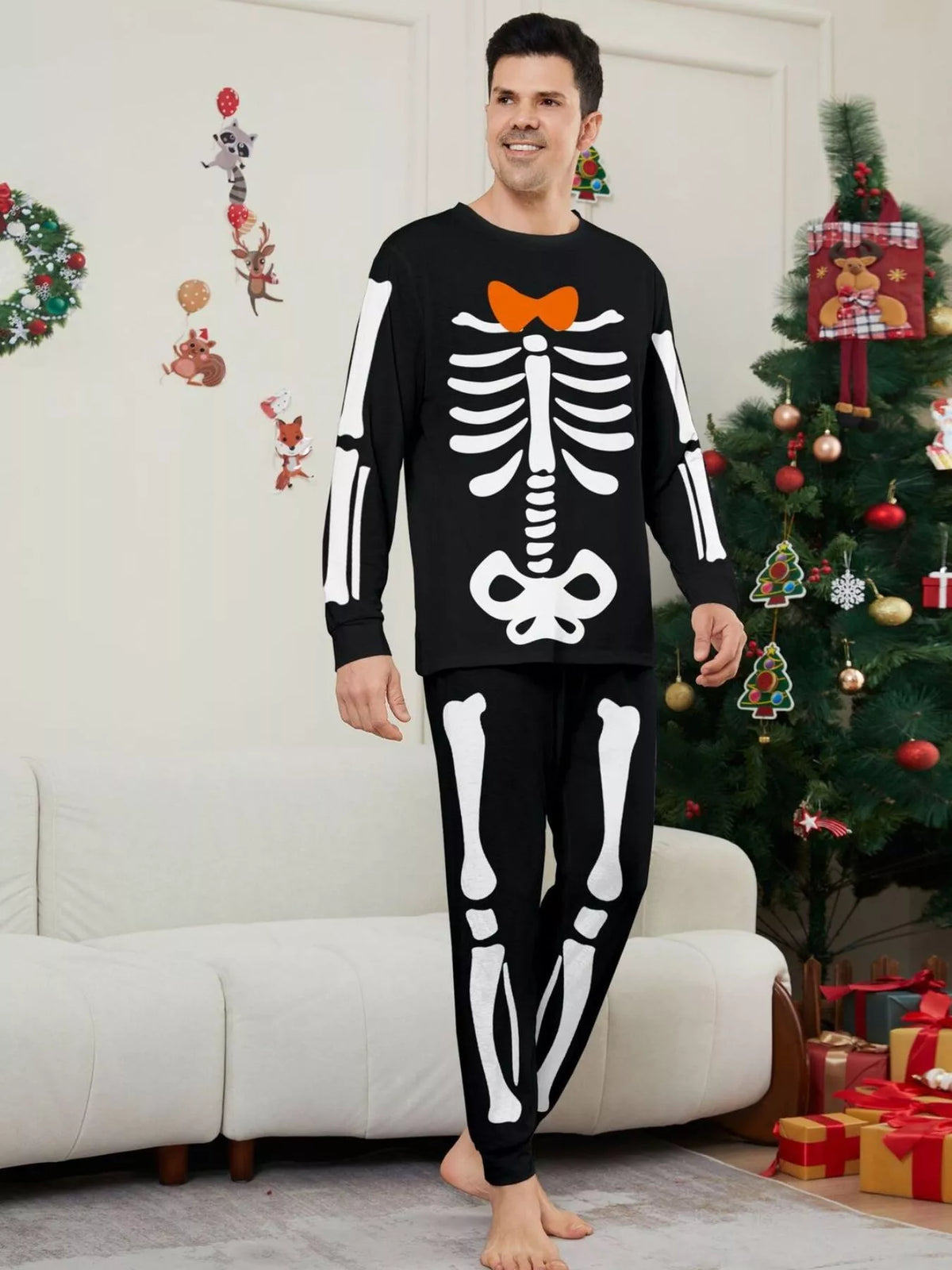Man modeling black pajamas with white skeleton graphics and an orange bow.