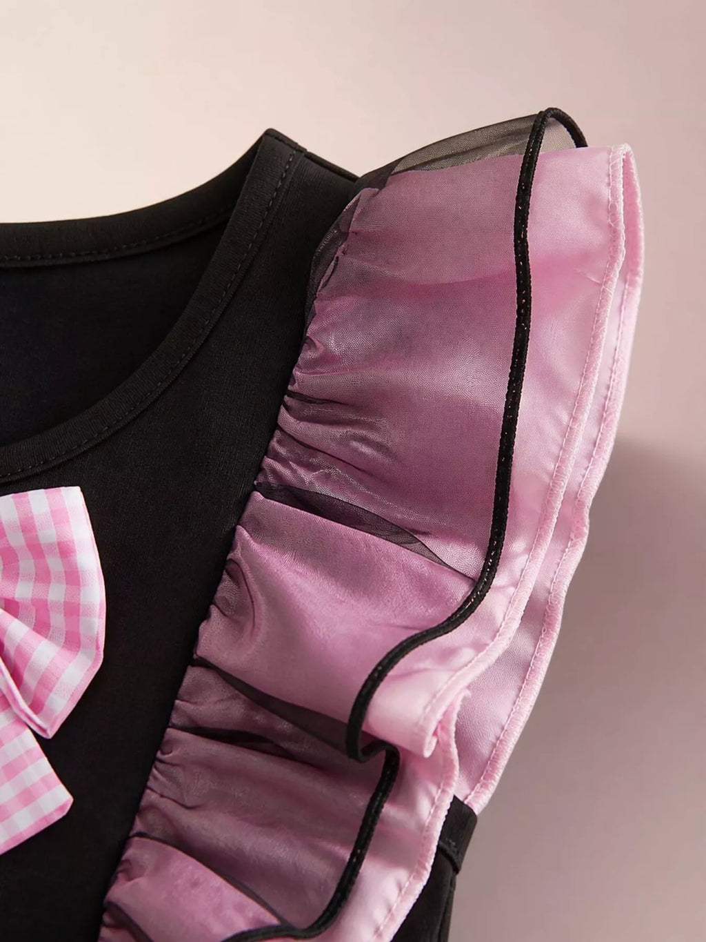 Close-up of the dress's sheer pink-and-black ruffled shoulder trim.