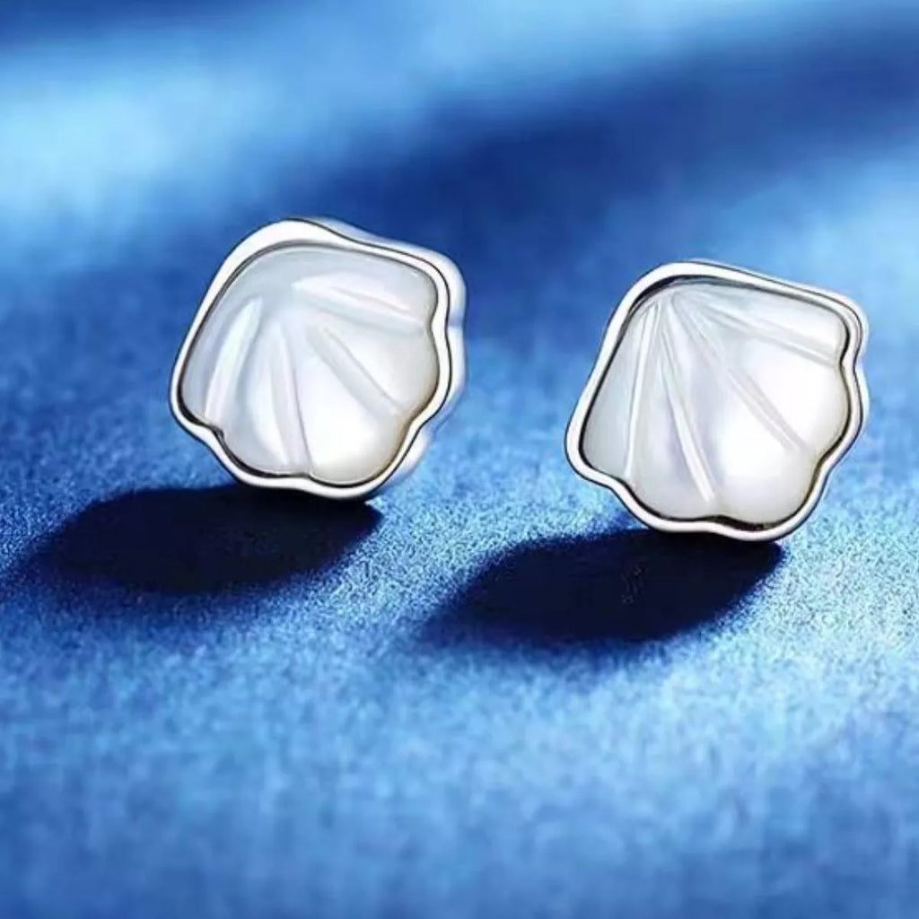 Silver-tone shell-shaped stud earrings with white centers — detail view