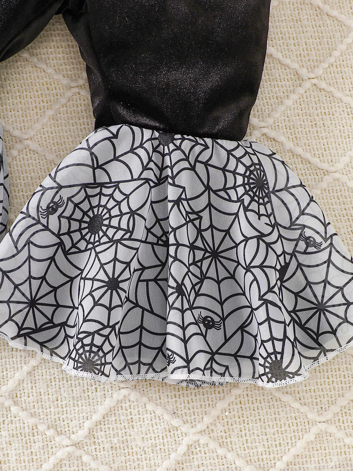 Close-up of the gray spiderweb-print flared pant hem.