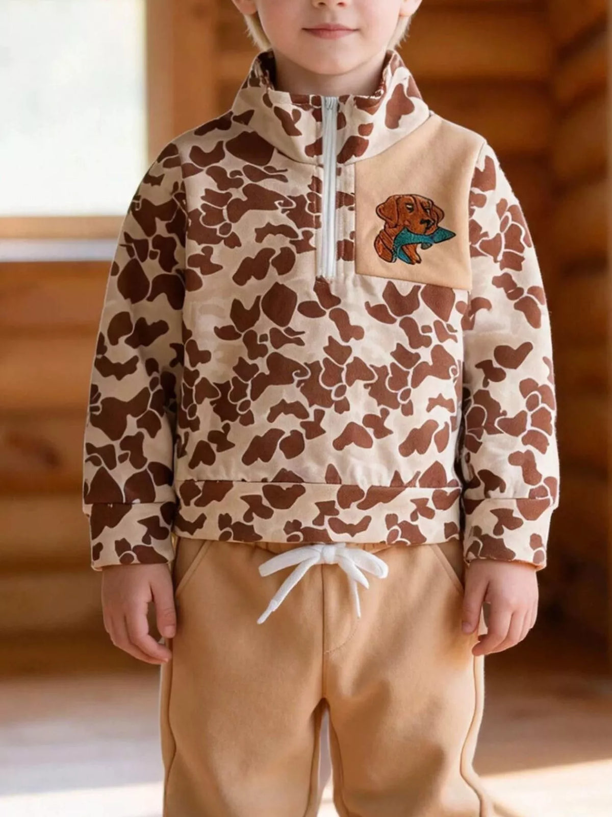 Tan camouflage quarter-zip top and tan joggers worn by a child