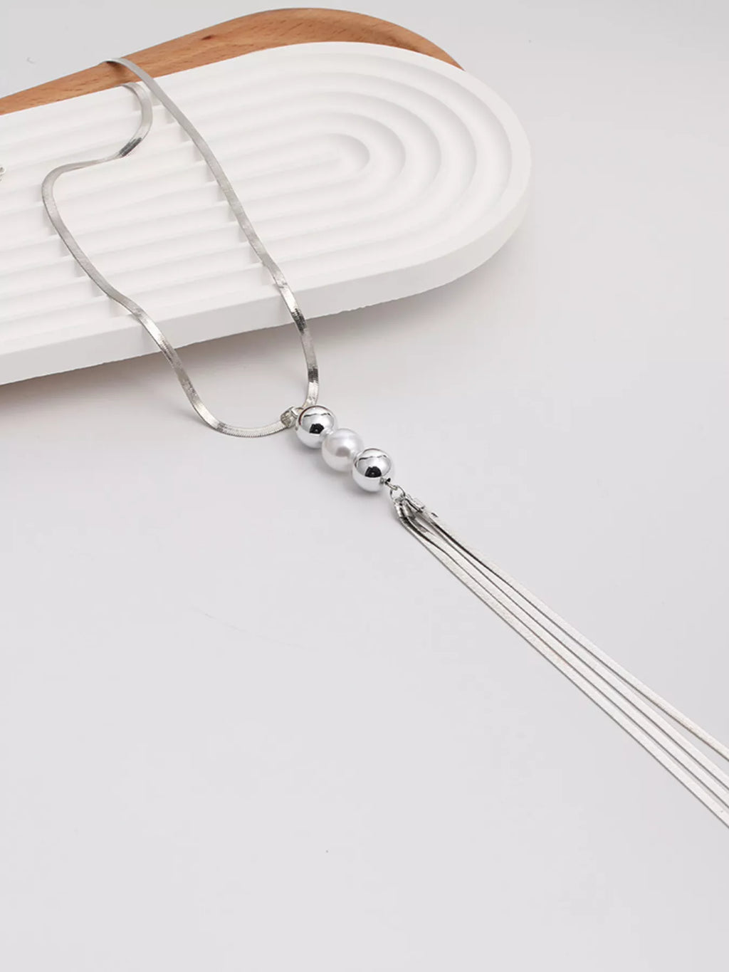 Long silver-tone necklace with bead accents and chain tassel — detail view