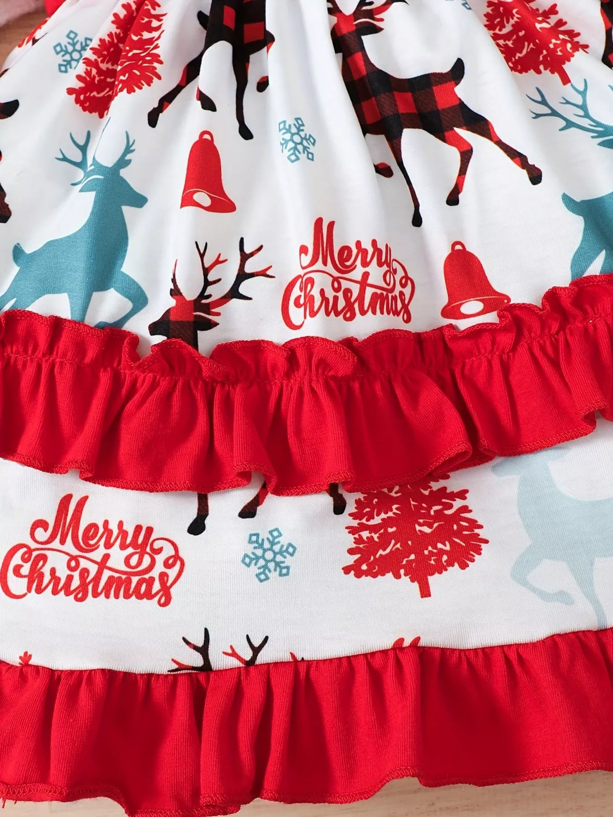 Close-up of the reindeer, Christmas tree and Merry Christmas print between red ruffles.