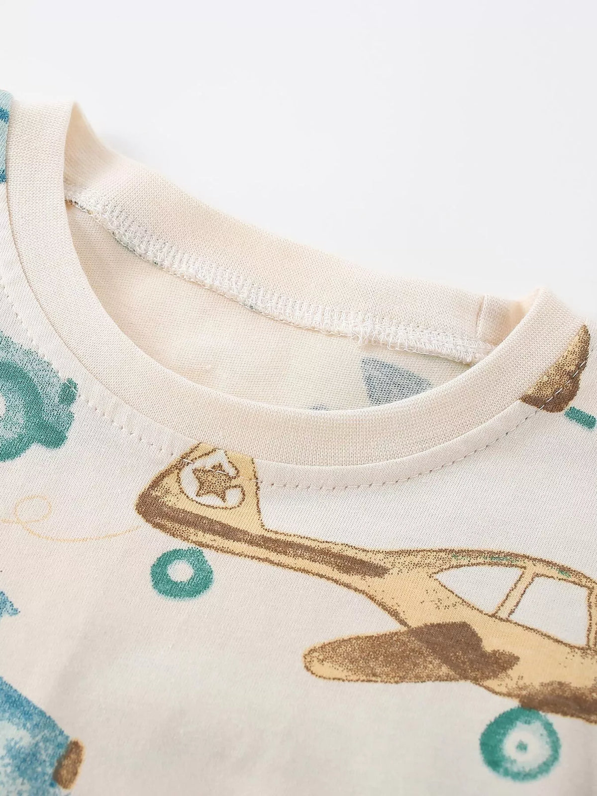 Close-up of the cream vehicle-print shirt's crew neckline.
