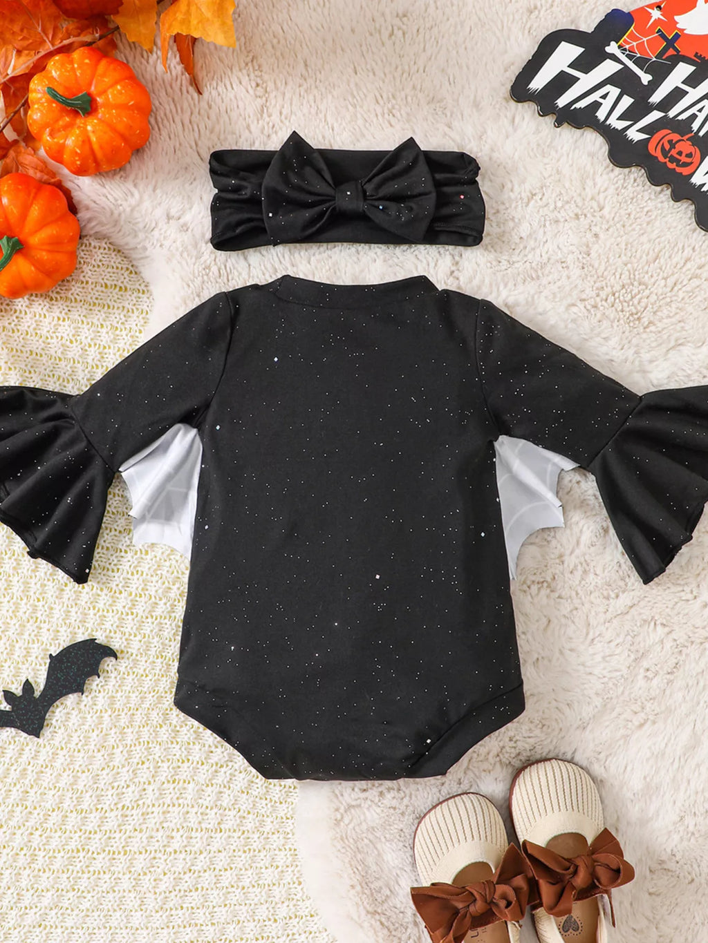 Black long-sleeve baby bodysuit with spiderweb sleeves and matching bow headband — back view
