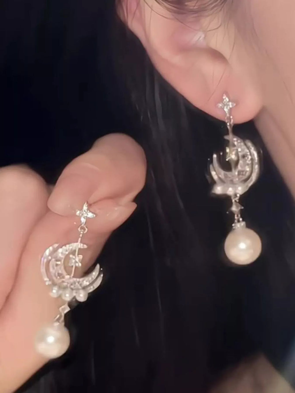 Moon and star dangle earrings with pearl-like bead drops worn on a model