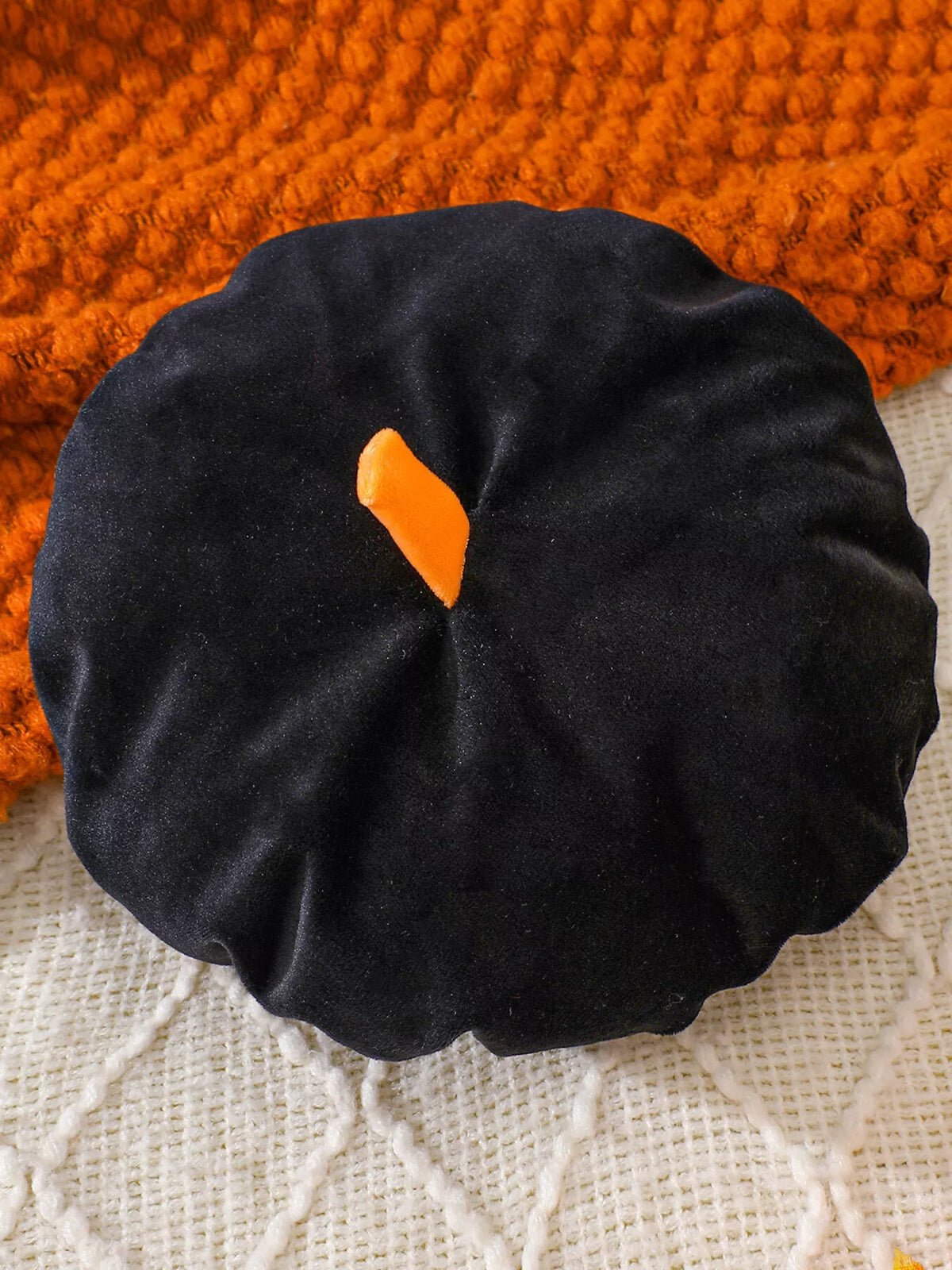 Black beret-style baby hat with an orange stem