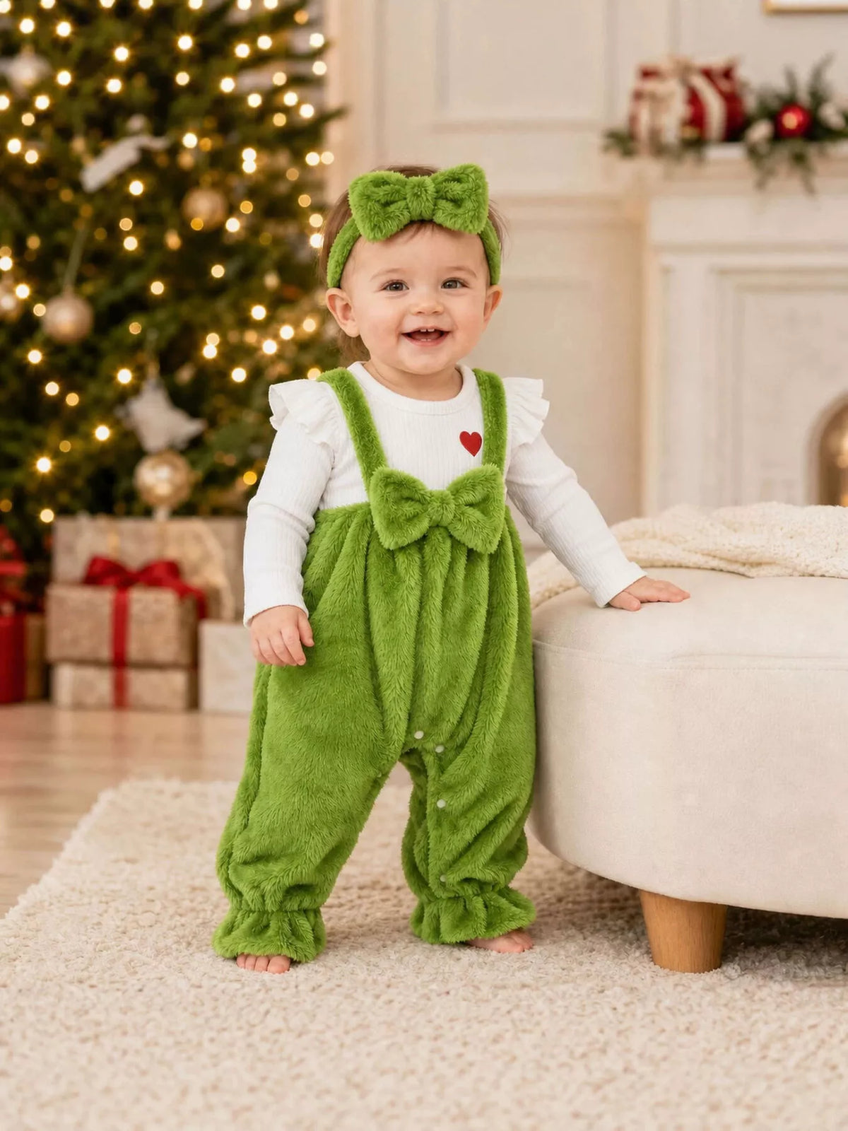 Green fuzzy baby overalls and matching bow headband with a white long-sleeve top worn by a baby