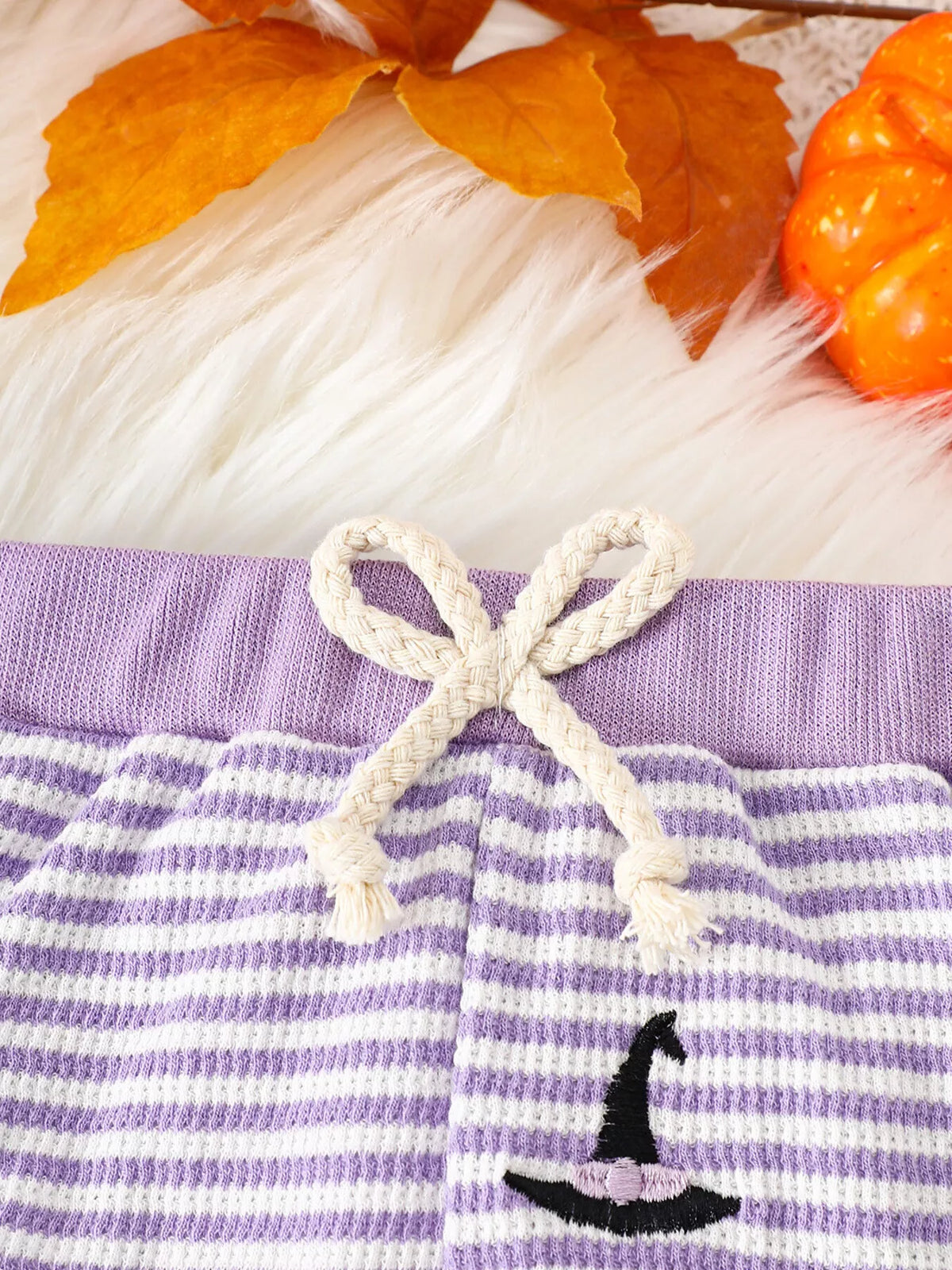 White drawstring waistband and witch-hat print on purple-striped pants