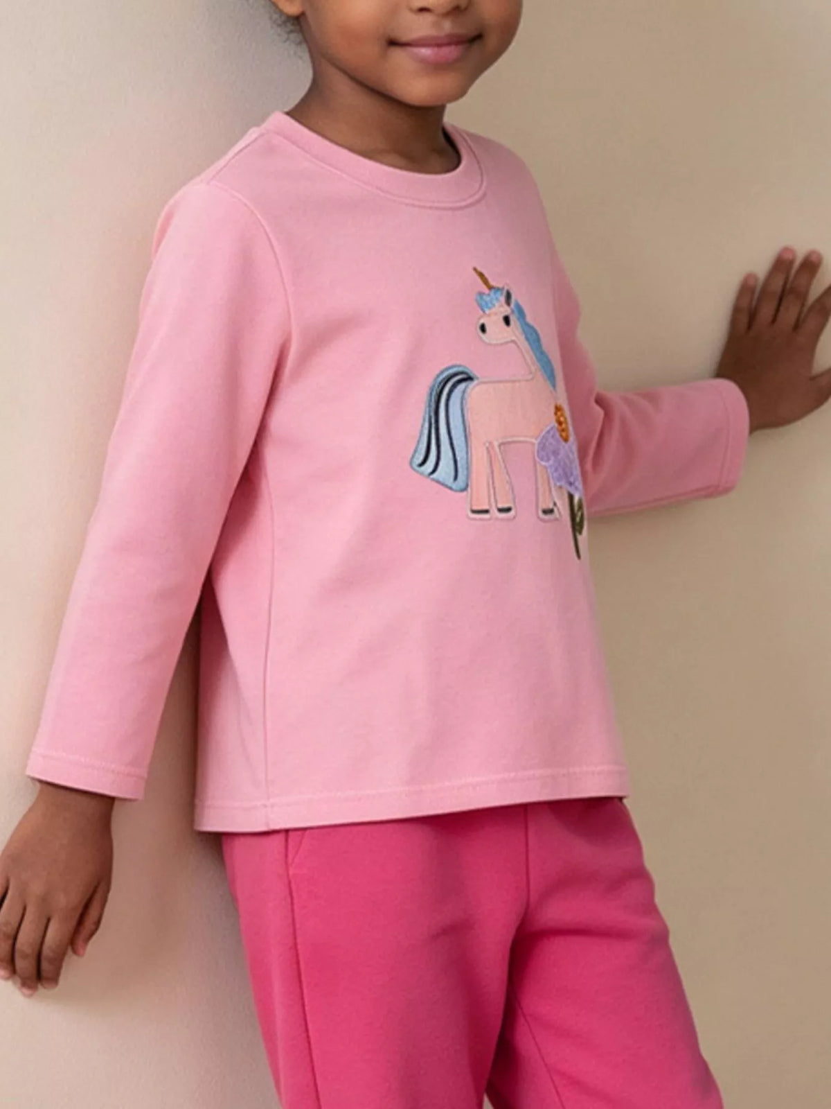 Long-sleeve children’s top with colorful embroidered graphics worn by a child