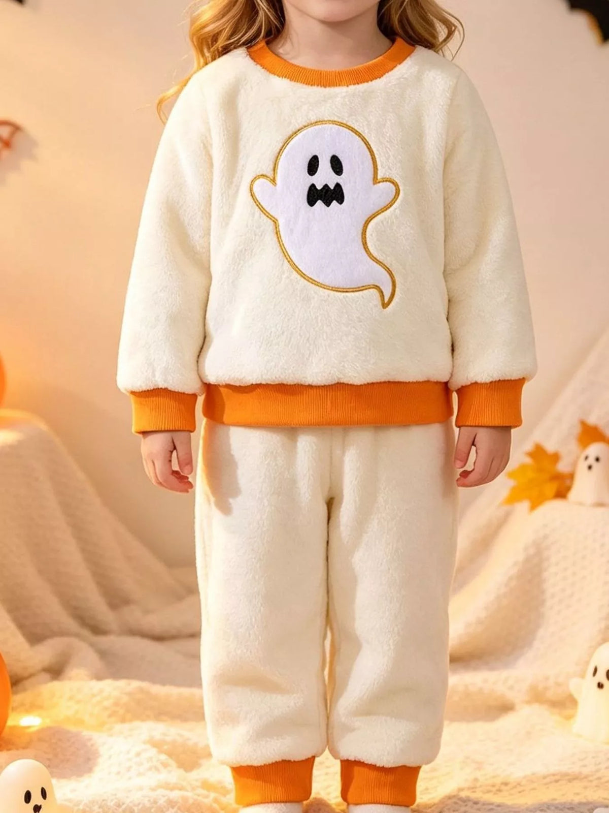 Cream ghost graphic top with orange trim and matching pants worn by a child