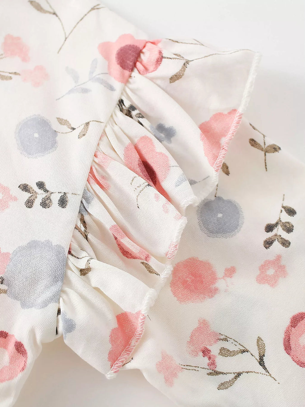 Ruffle sleeve seam and pastel floral fabric of the cream sweatshirt