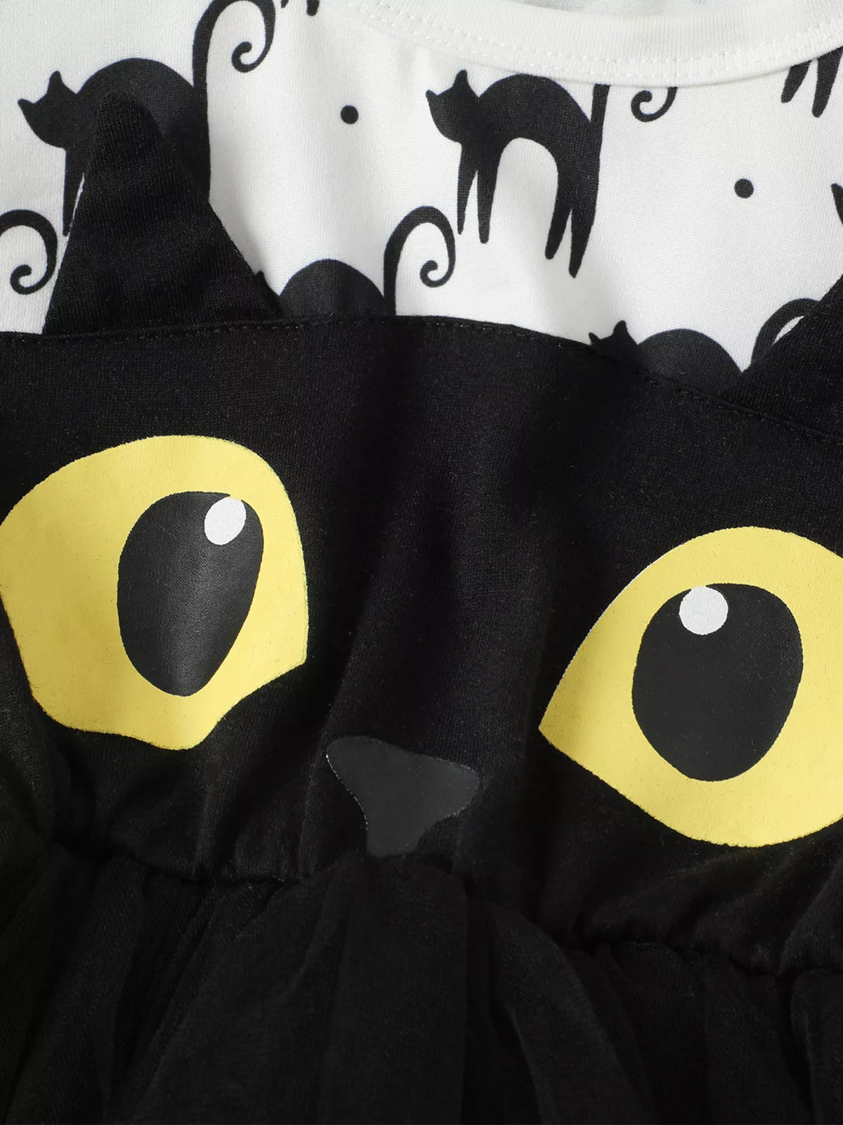 Close-up of the cat face, yellow eyes and black tulle on the white Halloween dress.