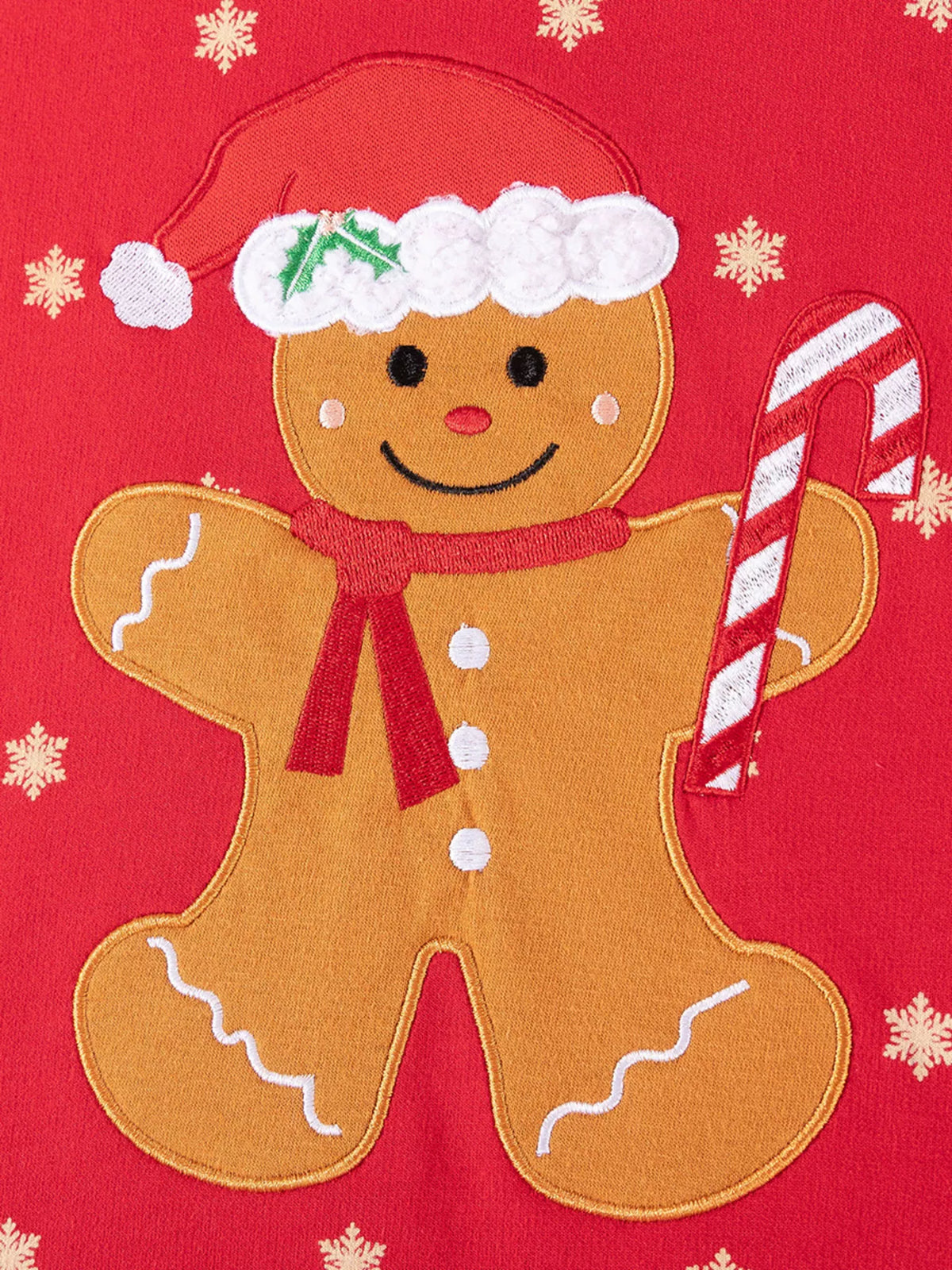 Close-up of the gingerbread character in a Santa hat holding a candy cane on the red top.