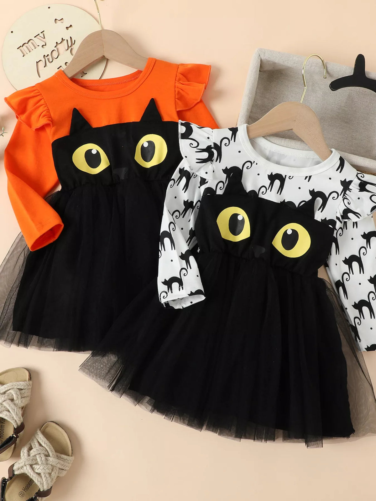 Orange and white children's black-cat Halloween dresses with black tulle skirts displayed together.