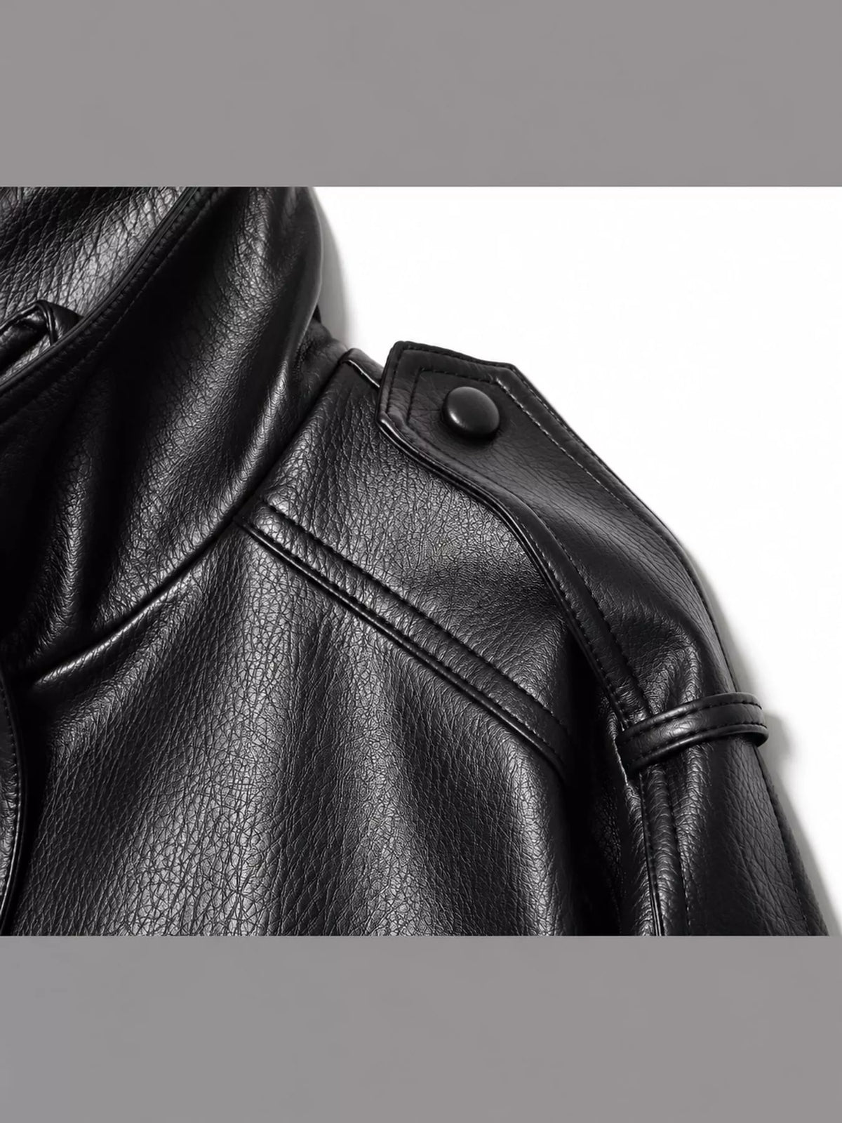 Close-up of the black jacket's textured finish and buttoned shoulder tab.