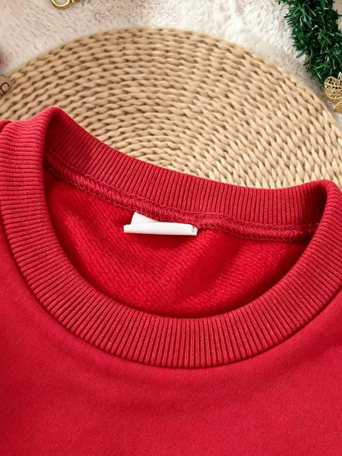 Ribbed red crew neckline of the children’s Santa sweatshirt