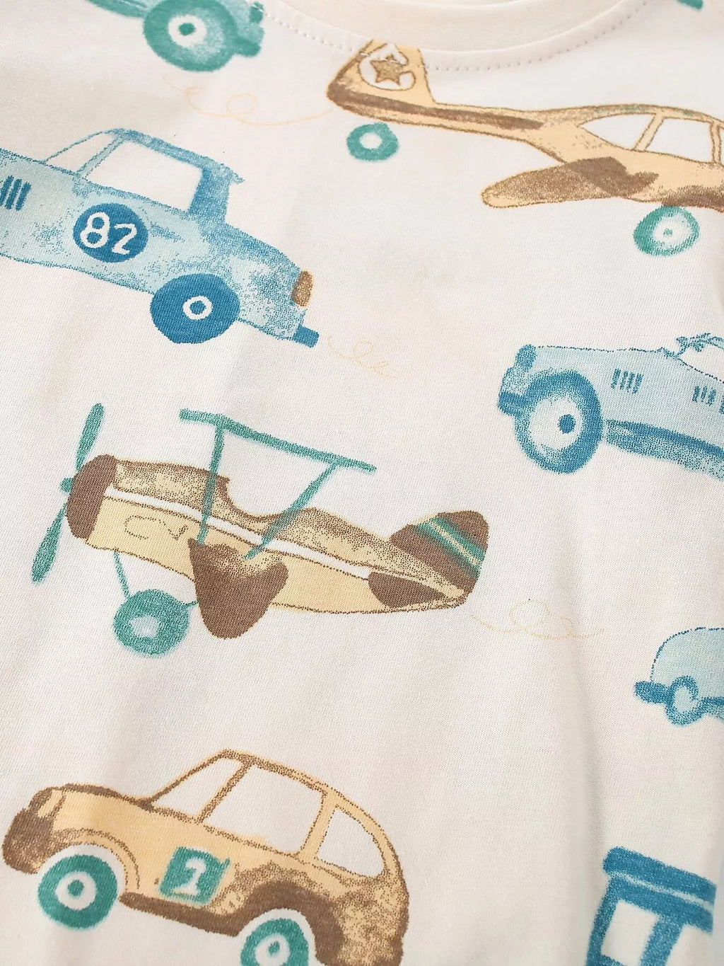 Close-up of the blue cars and tan airplane illustrations on the cream shirt.
